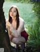 A young woman leaning against a tree in a park.