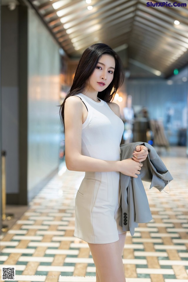 A woman in a white dress is posing for a picture.