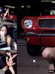 A woman in a red bikini sitting in front of a red car.