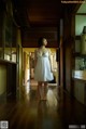 A woman in a white dress standing in a hallway.