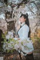 A woman in a white dress holding a sword in front of a tree.