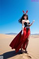 A woman in a red and black outfit standing in the desert.