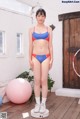 A woman in a blue and red bikini standing next to a pink ball.
