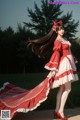 A woman in a red and white dress is posing for a picture.