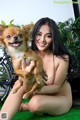 A naked woman holding a small dog in her arms.