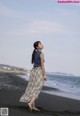 A woman standing on a beach next to the ocean.