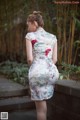 A woman in a white dress with red flowers on it.