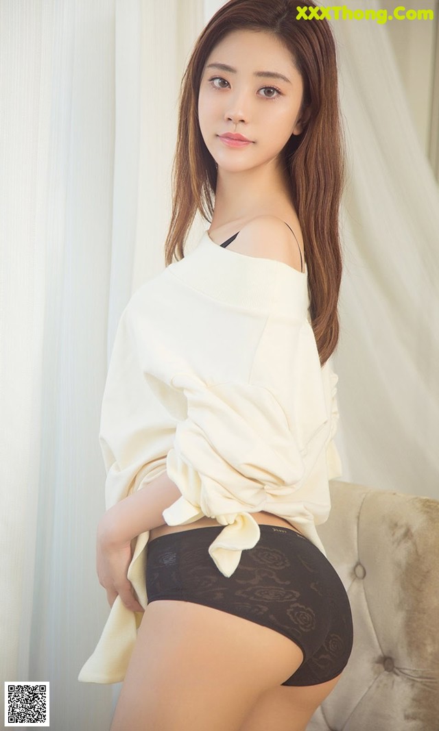 A woman in a white shirt and black panties posing for a picture.