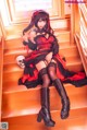 A woman in a red and black dress sitting on a set of stairs.