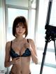 A woman in a black bra and panties standing in front of a camera.