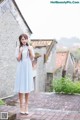 A woman in a blue dress standing on a brick walkway.